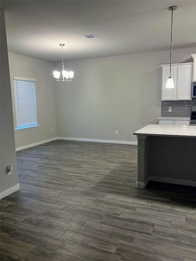 kitchen with pendant lighting, dark wood-type flooring, white cabinets, decorative backsplash, and a notable chandelier