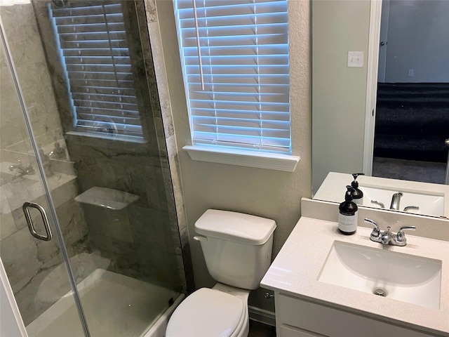 bathroom with a shower with door, vanity, and toilet