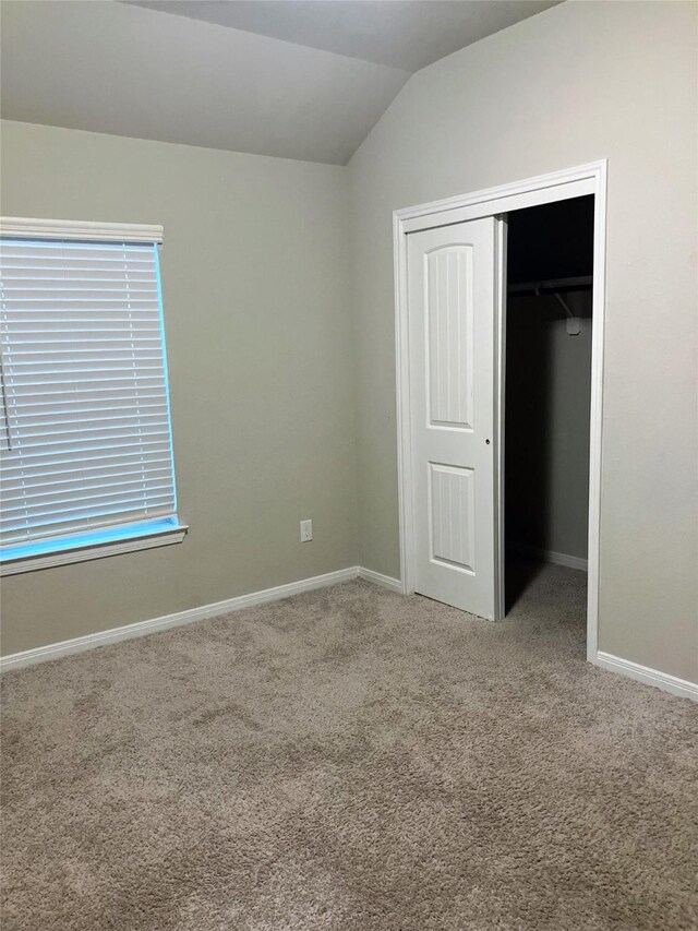 unfurnished bedroom with vaulted ceiling, carpet floors, and a closet