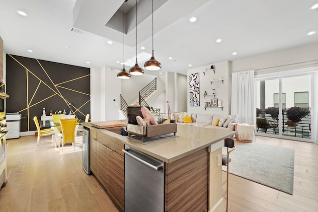 kitchen with pendant lighting, stainless steel dishwasher, a center island, and light hardwood / wood-style floors