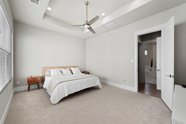 carpeted bedroom featuring a raised ceiling and ceiling fan