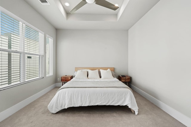 bedroom featuring light colored carpet, ceiling fan, and a tray ceiling