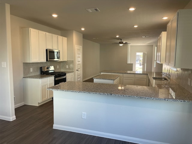 kitchen with white cabinetry, light stone counters, kitchen peninsula, and appliances with stainless steel finishes