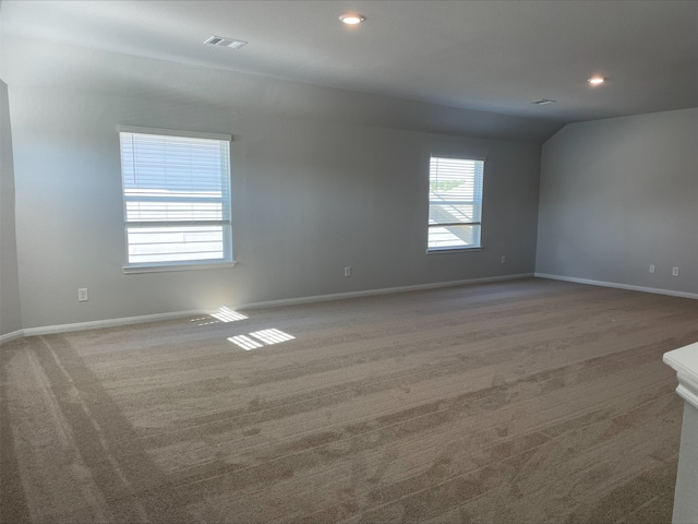 spare room featuring carpet floors and lofted ceiling