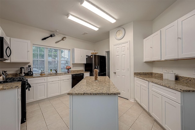 kitchen featuring white cabinets, a center island, light stone counters, and black appliances