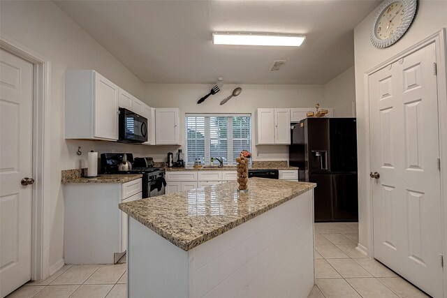 kitchen featuring black appliances, sink, a kitchen island, light stone counters, and white cabinetry