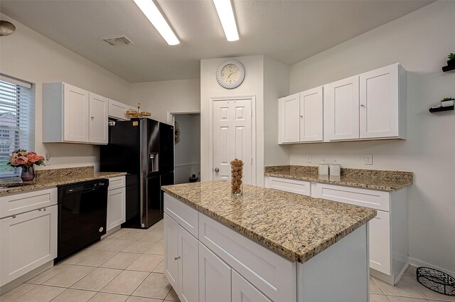 kitchen with black appliances, white cabinets, light tile patterned floors, a kitchen island, and light stone counters