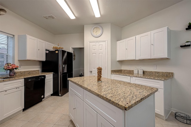 kitchen featuring light tile patterned flooring, white cabinetry, a center island, light stone counters, and black appliances