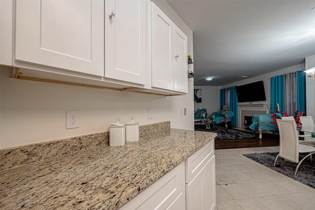 kitchen featuring white cabinets, light tile patterned floors, and light stone countertops