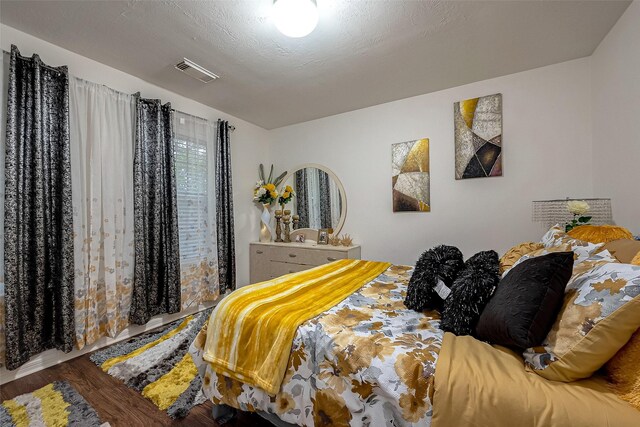 bedroom with a textured ceiling and hardwood / wood-style flooring