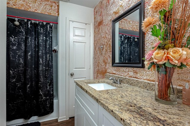 bathroom with hardwood / wood-style floors, vanity, and shower / tub combo