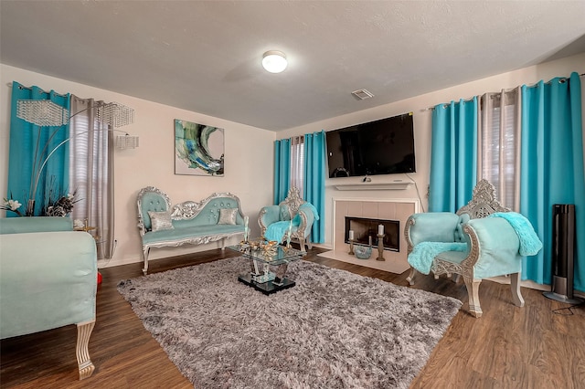 living area with a tile fireplace and hardwood / wood-style flooring