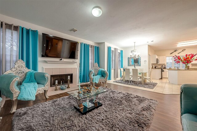 living room with a fireplace, light hardwood / wood-style floors, and a chandelier