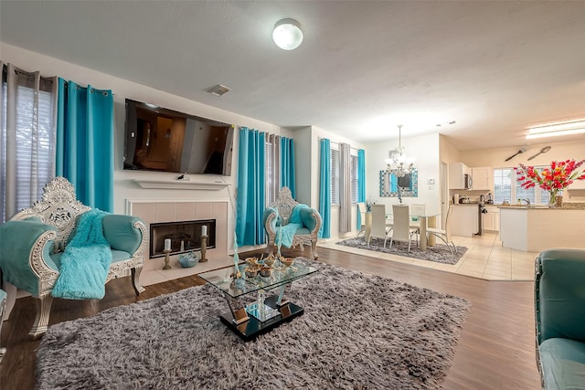 living room featuring an inviting chandelier, a fireplace, and light hardwood / wood-style floors