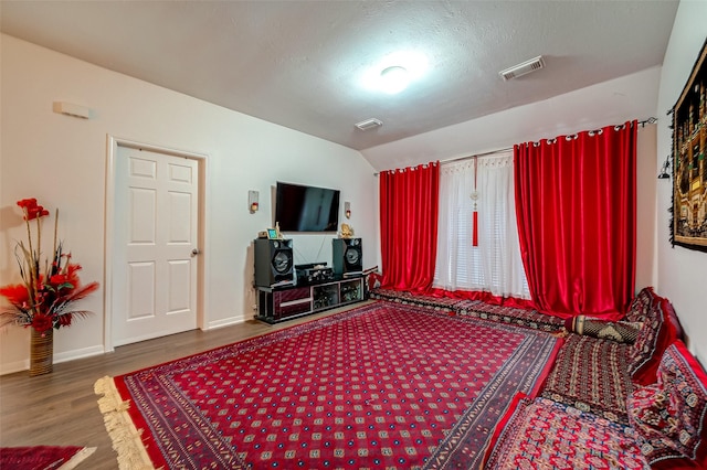 bedroom featuring a textured ceiling, wood-type flooring, and lofted ceiling