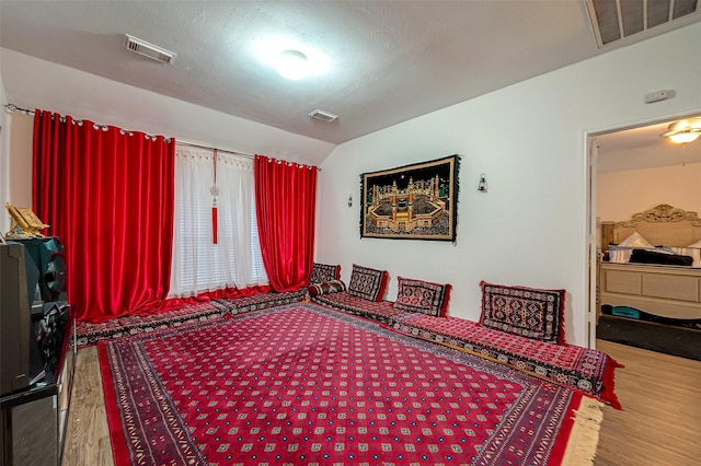 bedroom featuring hardwood / wood-style floors, lofted ceiling, and a textured ceiling