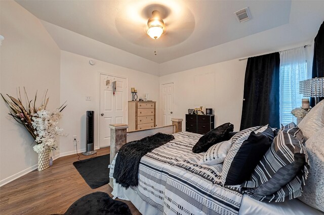 bedroom featuring dark hardwood / wood-style floors, ceiling fan, and a tray ceiling