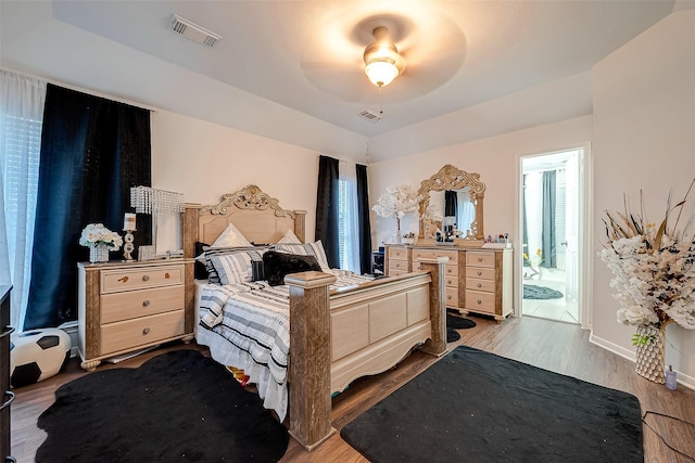 bedroom with ceiling fan, ensuite bathroom, and wood-type flooring