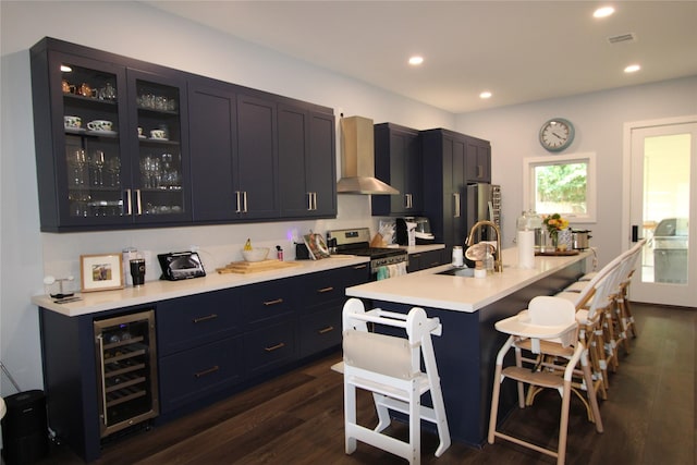 kitchen featuring sink, wall chimney exhaust hood, appliances with stainless steel finishes, a breakfast bar area, and beverage cooler