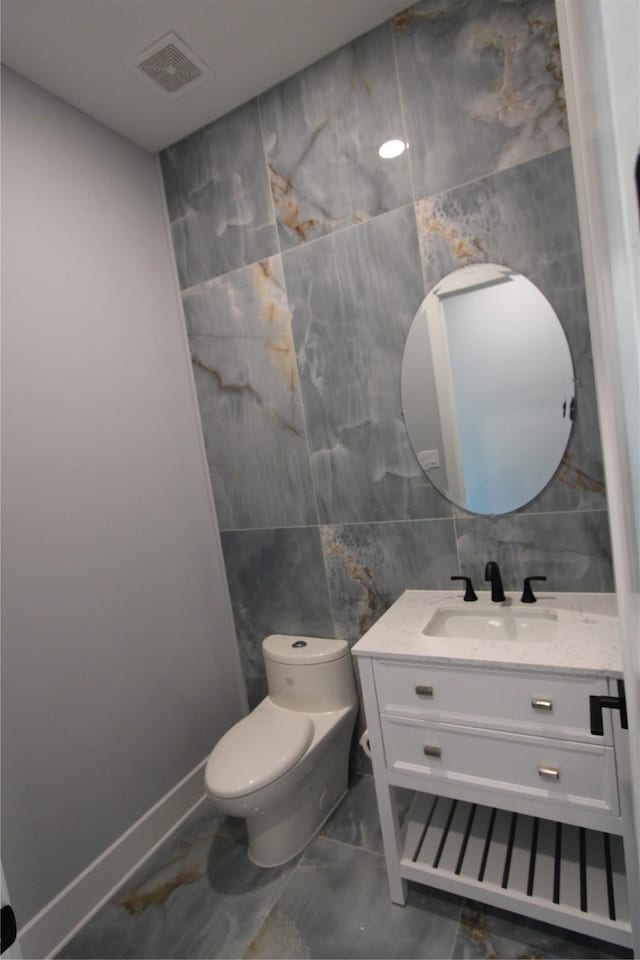 bathroom with vanity, tile walls, and toilet