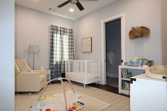 bedroom featuring ceiling fan and a crib