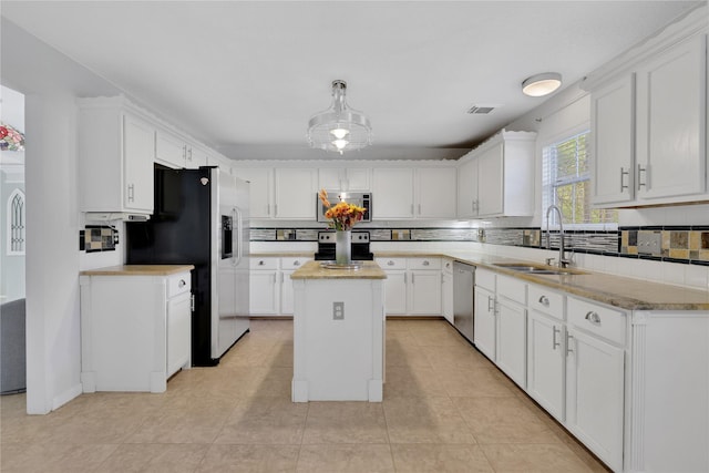 kitchen featuring white cabinets, a kitchen island, sink, and appliances with stainless steel finishes