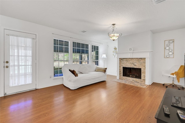 living room featuring a fireplace, hardwood / wood-style floors, a textured ceiling, and a chandelier