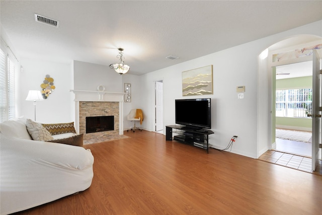 living room featuring hardwood / wood-style floors, a stone fireplace, and a wealth of natural light