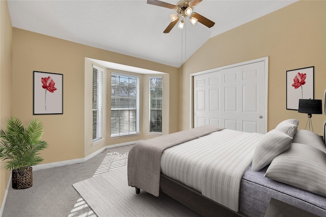 carpeted bedroom with ceiling fan, a closet, and lofted ceiling