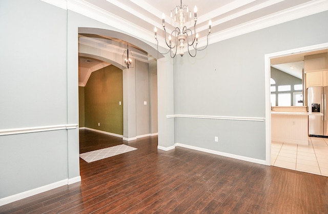 empty room with wood-type flooring, crown molding, and a notable chandelier