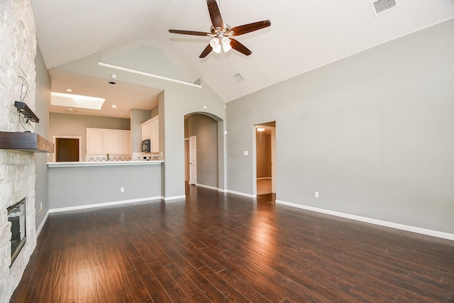 unfurnished living room featuring a stone fireplace, ceiling fan, high vaulted ceiling, and dark hardwood / wood-style floors