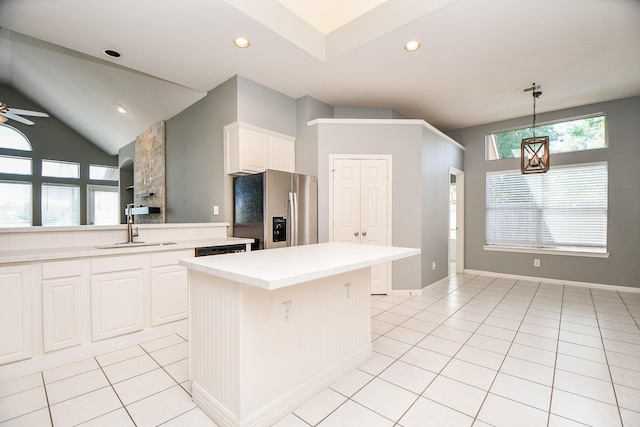 kitchen with a center island, light tile patterned floors, stainless steel refrigerator with ice dispenser, decorative light fixtures, and white cabinets