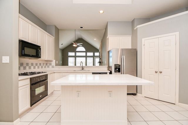 kitchen featuring a center island, sink, backsplash, vaulted ceiling, and black appliances