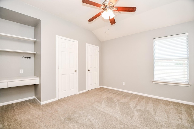 unfurnished bedroom featuring carpet flooring, ceiling fan, multiple closets, and vaulted ceiling