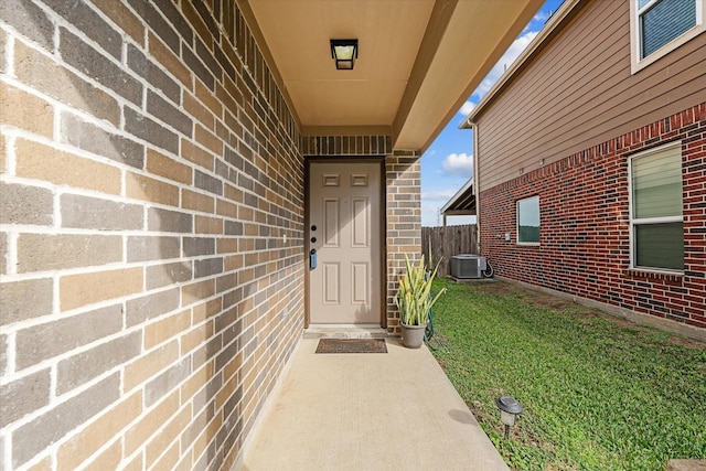 property entrance with cooling unit and a lawn