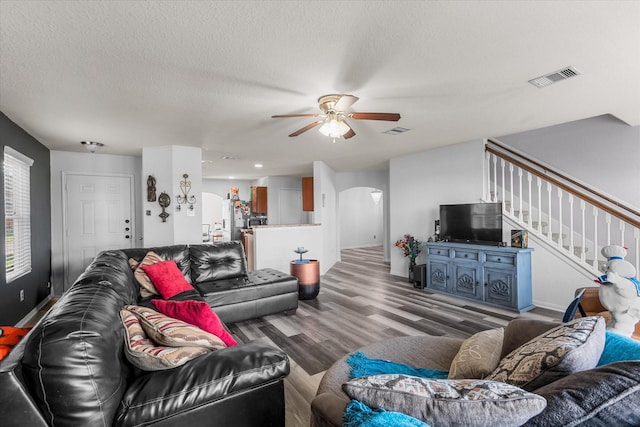 living room featuring hardwood / wood-style floors, ceiling fan, and a textured ceiling