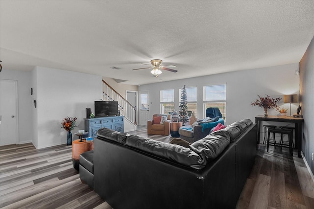 living room with ceiling fan, a textured ceiling, and hardwood / wood-style flooring