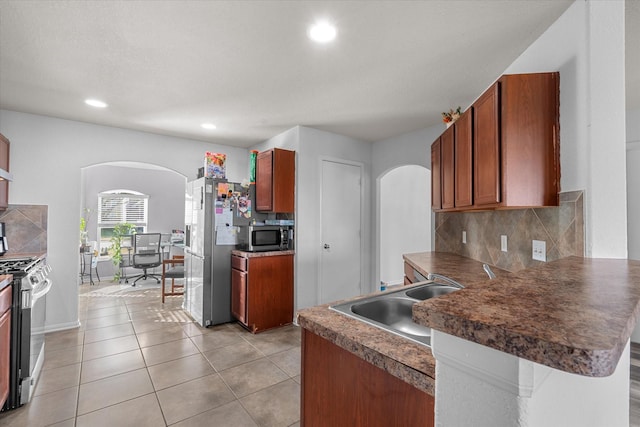 kitchen featuring sink, stainless steel appliances, backsplash, kitchen peninsula, and light tile patterned floors