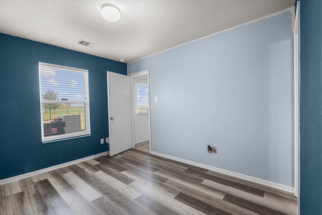 unfurnished room with wood-type flooring and a textured ceiling