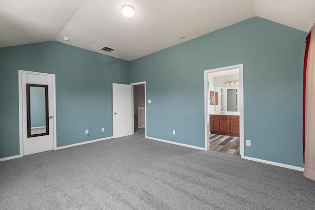 unfurnished bedroom featuring connected bathroom, carpet floors, and vaulted ceiling