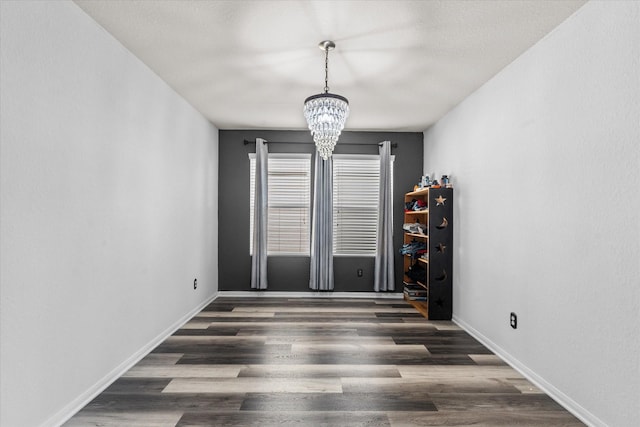 spare room featuring dark hardwood / wood-style floors and a chandelier