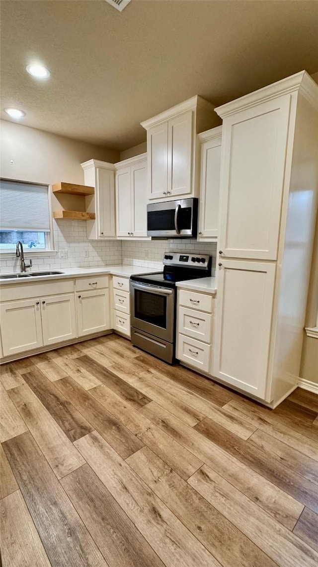 kitchen featuring white cabinets, appliances with stainless steel finishes, and light hardwood / wood-style floors