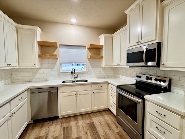 kitchen with white cabinetry, sink, backsplash, and appliances with stainless steel finishes