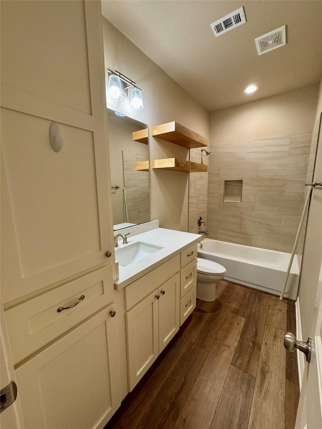 full bathroom with toilet, tiled shower / bath, wood-type flooring, and vanity