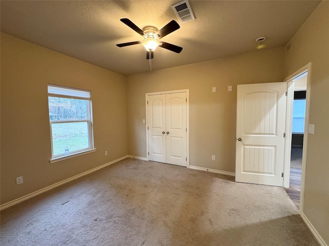 unfurnished bedroom featuring a textured ceiling, ceiling fan, carpet, and a closet