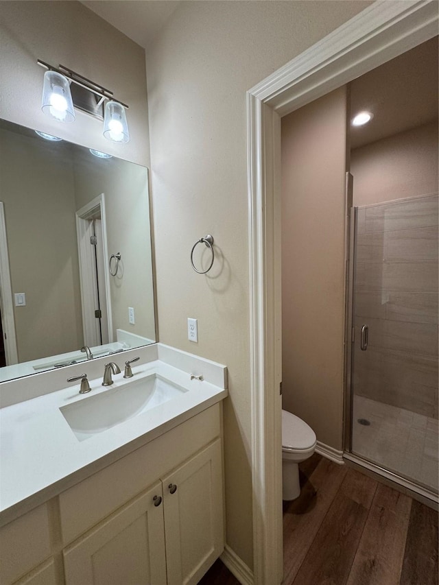 bathroom with wood-type flooring, toilet, vanity, and walk in shower