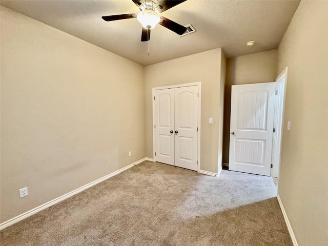 unfurnished bedroom with a textured ceiling, ceiling fan, a closet, and light colored carpet