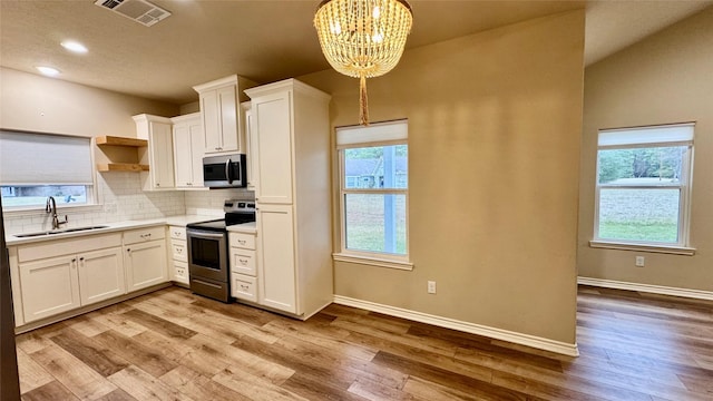 kitchen with decorative light fixtures, sink, white cabinetry, appliances with stainless steel finishes, and a chandelier