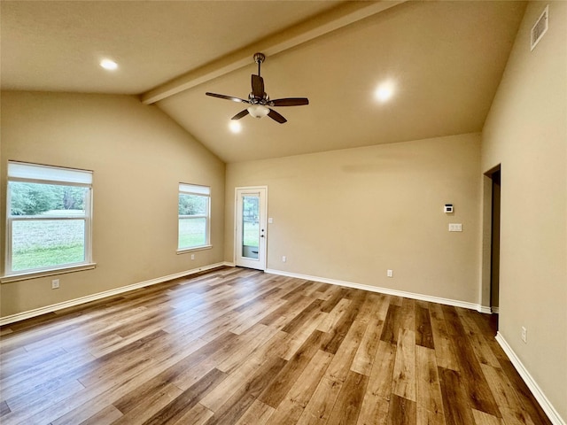 spare room with hardwood / wood-style flooring, a healthy amount of sunlight, and vaulted ceiling with beams