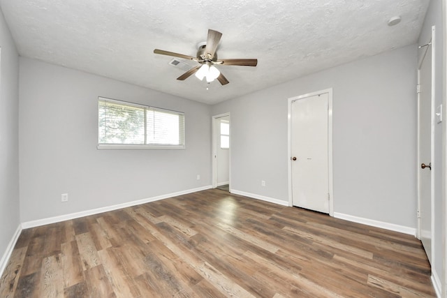 empty room with a textured ceiling, ceiling fan, and dark wood-type flooring